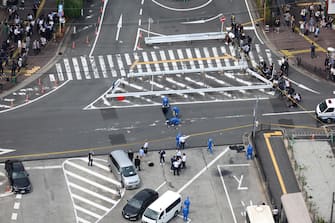 epa10058735 Police investigate the crime scene, where Former Japanese Prime Minister Shinzo Abe was shot during an Upper House election campaign, outside Yamato-Saidaiji Station of Kintetsu Railway in Nara, western Japan, 08 July 2022.  EPA/JIJI PRESS JAPAN OUT EDITORIAL USE ONLY/