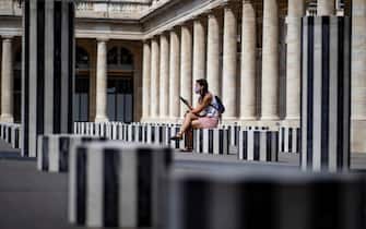 epa08614397 A woman wearing a protective face mask sits amid the Buren Columns, an art installation by David Buren officially entitled 'Les Deux Plateaux', in the Palais Royal in Paris, France, 20 August 2020. Paris has been declared a zone of 'active circulation' for the Covid19 coronavirus as cases surged in recent weeks, prompting British tourists vacationing in France to be recalled back to their homeland or face fourteen days quarantine upon arrival. The spike in Covid cases and foreign tourist exodus is affecting Paris' tourism industry, with media reports of hotel reservations down by 86 per cent comparatively to last year.  EPA/IAN LANGSDON