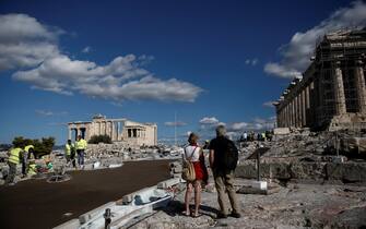 epa08788592 Tourists watch workers cementing the pathway to the Parthenon temple at the archaeological site of the Acropolis hill in Athens, Greece, 31 October 2020, to improve access for visitors with mobility issues, special needs and the elderly, according to an announcement by the Ministry of Culture.  EPA/YANNIS KOLESIDIS