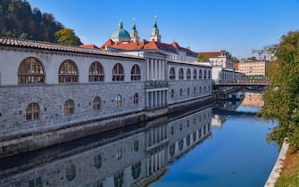 Slovenia, Ljubljana, Plecnik Colonnade and Central Market with the Cathedral of St Nicholas behind and the Ljubljanica River in the foreground. 