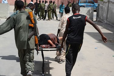 GRAPHIC CONTENT
Somali policemen carry the remains of a victim on April 14, 2013, in Mogadishu, after a suicide bomber attack in the regional court premises that left several dead. Gunmen wearing suicide vests stormed the main court complex in Mogadishu on April 14, killing at least five people before holing themselves up as Somali and African forces surrounded the building. Several people were wounded minutes later when a remote-detonated car bomb went off as a Turkish aid convoy drove by near the airport, in some of the worst violence to hit Mogadishu in months.   AFP PHOTO / MOHAMED ABDIWAHAB        (Photo credit should read Mohamed Abdiwahab/AFP via Getty Images)