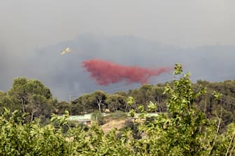epa10076244 A firefighting aircraft drops water on a forest fire originated in Pont de Vilomara, Spain, 17 July 2022. The fire has burnt 440 hectares so far.  EPA / TONI ALBIR