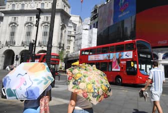 epa10079567 People use umbrellas to shelter from the sun in London, Britain, 19 July 2022. The Met Office has issued a red extreme heat warning as the UK could have its hottest day on record this week, with temperatures forecast to hit up to 41 degrees Celsius.  EPA/NEIL HALL