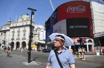 epa10079570 A man uses an umbrella hat to shelter from the sun in London, Britain, 19 July 2022. The Met Office has issued a red extreme heat warning as the UK could have its hottest day on record this week, with temperatures forecast to hit up to 41 degrees Celsius.  EPA/NEIL HALL