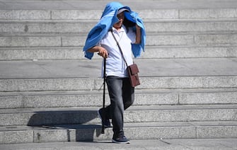 epa10079569 A man uses a jacket to shelter from the sun in London, Britain, 19 July 2022. The Met Office has issued a red extreme heat warning as the UK could have its hottest day on record this week, with temperatures forecast to hit up to 41 degrees Celsius.  EPA/NEIL HALL