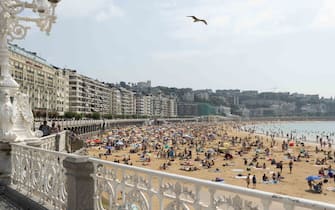 View of La Concha beach in San Sebastian crowded of people, on July 20, 2021. Beachgoers have gathered at the beaches on San Sebastian, Spain at temperatures of almost 30 degrees.  Many tourists enjoy sun, sand, waves and sea at the beaches of Spain.  (Photo by Manuel Balles / NurPhoto via Getty Images)