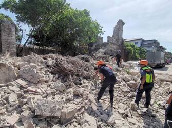 epa10093370 A handout photo made available by the Bureau of Fire Protection (BFP) shows rescuers and and a policeman inspecting a collapsed structure following an earthquake in Vigan, Ilocos Sur province, Philippines, 27 July 2022. A strong quake with a 7.3 magnitude intensity that jolted Abra province in the main island of Luzon was registered by Philippine Institute of Volcanology and Seismology.  EPA/Bureau of Fire Protection (BFP) / HANDOUT  HANDOUT EDITORIAL USE ONLY/NO SALES