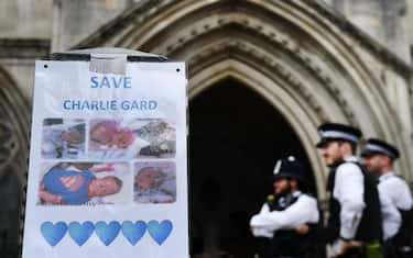 epa06084635 Police stands behind a poster outside the High Court during the Charlie Guard case in London, Britain, 13 July 2017. Connie Yates and Chris Gard earlier 13 July had delivered a petition to Great Ormond Street Hospital calling for Charlie to be allowed to travel and to receive treatment in the US. The High Court is expected to make a decision on the case this Thursday, 13 July.  EPA/ANDY RAIN