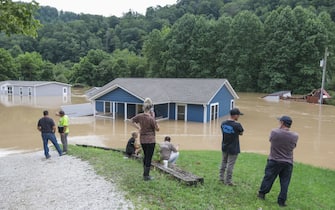 A family watches their home submerged by floodwaters from the North Fork of the Kentucky River in Jackson, Kentucky on July 28, 2022. - Flash flooding caused by torrential rains has killed at least eight people in eastern Kentucky and left some residents stranded on rooftops and in trees, the governor of the south-central US state said Thursday. (Photo by LEANDRO LOZADA / AFP) (Photo by LEANDRO LOZADA/AFP via Getty Images)