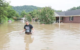 A young woman walks through waist-deep water next to a house flooded by the waters of the North Fork of the Kentucky River in Jackson, Kentucky on July 28, 2022. - At least eight people have died after torrential rains caused massive flooding in eastern Kentucky, leaving a number of people stranded on rooftops and in trees, the governor of the southeastern US state said Thursday. (Photo by LEANDRO LOZADA / AFP) (Photo by LEANDRO LOZADA/AFP via Getty Images)