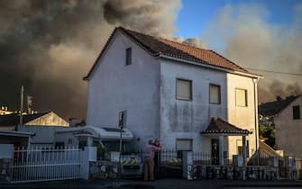 People stand outside their houses watching the progression of a wildfire in Mafra on July 31, 2022. (Photo by PATRICIA DE MELO MOREIRA / AFP) (Photo by PATRICIA DE MELO MOREIRA/AFP via Getty Images)