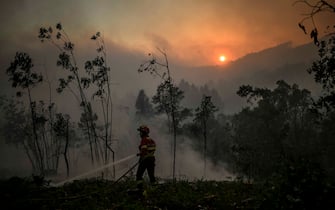 TOPSHOT - A firefighter tackles a wildfire at the village of Asseiceira Pequena in Mafra on July 31, 2022. (Photo by PATRICIA DE MELO MOREIRA / AFP) (Photo by PATRICIA DE MELO MOREIRA / AFP via Getty Images)