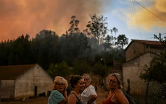 TOPSHOT - People stand outside their houses watching the progression of a wildfire in Mafra on July 31, 2022. (Photo by PATRICIA DE MELO MOREIRA / AFP) (Photo by PATRICIA DE MELO MOREIRA / AFP via Getty Images)