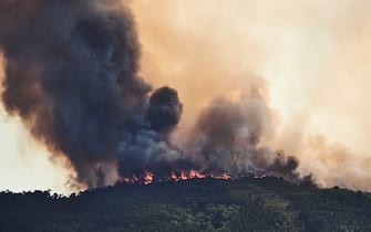 MAFRA, PORTUGAL - JULY 31: A large plume of smoke and flames are seen at a forest fire being fought by 321 firefighters, 84 vehicles and 9 specialized aircraft on July 31, 2022 in Mafra, Portugal.  The rise in temperatures this weekend is causing a new wave of forest fires in the country, especially in the central and northern regions.  The fires that most concern the authorities this Sunday afternoon are active in the municipalities of OurÃ © m, Mafra and PaÃ§os de Ferreira, with some 700 firefighters and 20 aerial means fighting them.  (Photo by Horacio Villalobos # Corbis / Corbis via Getty Images)