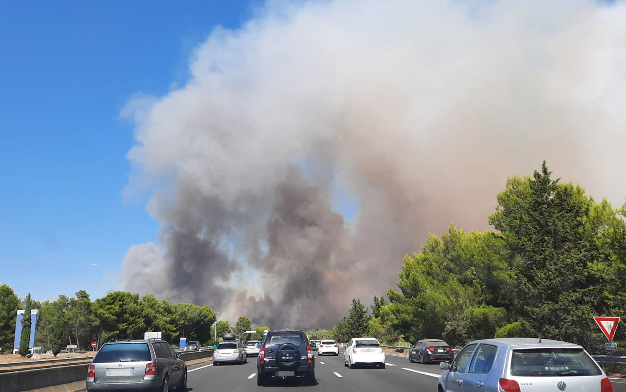 This image taken from a car window along a highway on July 31, 2022, shows thick white smoke from a fire near Aubais, southern France.  - According to the French Interior Minister, the fire has taken out 200 hectares and injured four firefighters.  (Photo by Benjamin GALY / AFP) (Photo by BENJAMIN GALY / AFP via Getty Images)