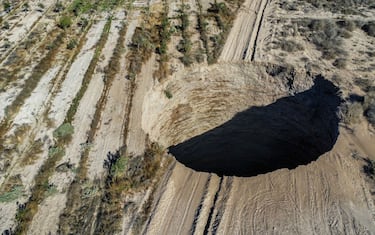 TOPSHOT - Aerial view taken on August 1, 2022, showing a large sinkhole that appeared over the weekend near the mining town of Tierra Amarilla, Copiapo Province, in the Atacama Desert in Chile. - A 100-metre security perimeter has been erected around the hole which appeared in the Tierra Amarilla municipality near the Alcaparrosa mine operated by Canadian firm Lundin Mining. (Photo by JOHAN GODOY / AFP) (Photo by JOHAN GODOY/AFP via Getty Images)