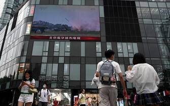 People walk in front of a large screen showing a news broadcast about China's military exercises encircling Taiwan, in Beijing on August 4, 2022. - China's largest-ever military exercises encircling Taiwan kicked off August 4, in a show of force straddling vital international shipping lanes after a visit to the island by US House Speaker Nancy Pelosi. (Photo by Noel Celis / AFP) (Photo by NOEL CELIS/AFP via Getty Images)
