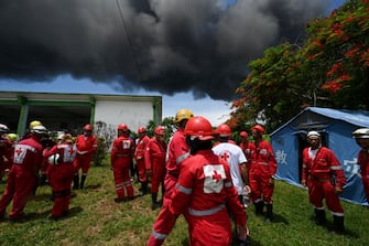 Firefighters rest near the fire on oil tanks in Matanzas, Cuba, on August 6, 2022. - The fire caused by lightning on Friday in a fuel depot in Matanzas, in western Cuba, spread to a second tank at dawn this Saturday and caused 49 injuries, official sources reported. (Photo by YAMIL LAGE / AFP) (Photo by YAMIL LAGE/AFP via Getty Images)