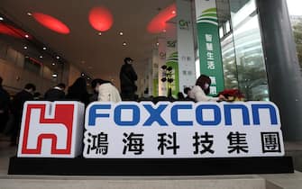 epa08918174 People work next to the logo of Foxconn Technology Group, during the ceremonial opening of Foxconn Research institute in Taipei, Taiwan, 04 January 2021. According to news reports, Foxconn Technology Group is in talks to China based electric-vehicle startup company Byton LTD. for funding that could mark a large bet on the electric car business.  EPA/RITCHIE B. TONGO