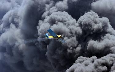 epa10111818 A plane flies over the cloud of smoke generated by the fire in a fuel depot, in Matanzas, Cuba, 08 August 2022. A third tank collapsed on the same day in the industrial area of fuel depots in the city of Matanzas in western Cuba, where a serious industrial fire, unprecedented since 05 August is still active, government authorities reported. The fire has left one person dead, 121 injured, and 17 missing, according to official reports.  EPA/Ernesto Mastrascusa