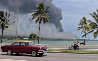 epa10111768 The column of smoke generated by the fire in a fuel depot in Matanzas, Cuba, 08 August 2022. A third tank collapsed on the same day in the industrial area of fuel depots in the city of Matanzas in western Cuba, where a serious industrial fire, unprecedented since 05 August is still active, government authorities reported. The fire has left one person dead, 121 injured, and 17 missing, according to official reports.  EPA/Ernesto Mastrascusa