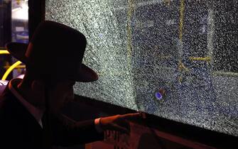 A man points at a bullet impact in a bus window after an attack outside Jerusalem's Old City, August 14, 2022. - Seven people were injured, two of them critically, after a shooting attack on a bus in Jerusalem's Old City, Israeli police and the national emergency medical services said early August 14, 2022. (Photo by AHMAD GHARABLI / AFP) (Photo by AHMAD GHARABLI / AFP via Getty Images)