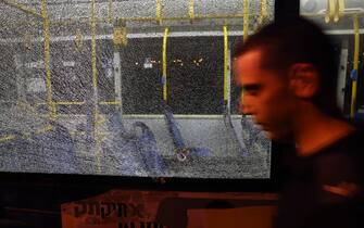 A man walks past a bullet impact in a bus window after an attack outside Jerusalem's Old City, August 14, 2022. - Seven people were injured, two of them critically, after a shooting attack on a bus in Jerusalem's Old City, Israeli police and the national emergency medical services said early August 14, 2022. (Photo by AHMAD GHARABLI / AFP) (Photo by AHMAD GHARABLI / AFP via Getty Images)