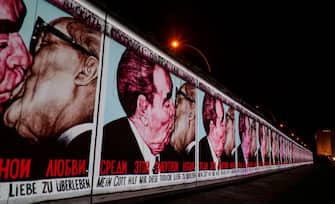 TOPSHOT - The mural painting "My God, Help Me to Survive This Deadly Love" by Russian painter Dmitri Vrubel, depicting the kiss between then Soviet leader Leonid Brezhnev (L) and East German leader Erich Honecker is  projected on a stretch of the Berlin wall at the so-called East-side Gallery during the city-wide kick-off of the festival week to celebrate the 30th anniversary of the November 9,1989 fall of the Berlin Wall, in Berlin on November 4, 2019. - Germany marks three decades since the fall of the Berlin Wall this week with main celebrations on November 9, 2019. (Photo by John MACDOUGALL / AFP) (Photo by JOHN MACDOUGALL/AFP via Getty Images)