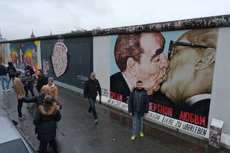 BERLIN, GERMANY - NOVEMBER 06: Visitors snap photos of a mural by artist Dmitry Vrubel that shows former Soviet Union leader Leonid Brezhnev kissing former east German leader Erich Honecker at a still-standing section of the former Berlin Wall called the East Side Gallery on November 6, 2019 in Berlin, Germany. November 9 will mark the 30th anniversary of the fall of the Wall that quickly led to the collapse of the communist East German government. Revolutions across other communist countries of the East Bloc soon followed. The Berlin Wall, built by the communist authorities of East Germany, stood from 1961 until 1989 and prevented people fleeing from East to West Berlin. At least 136 people, many of them shot dead by East German border guards, were killed trying to escape.  (Photo by Sean Gallup/Getty Images)