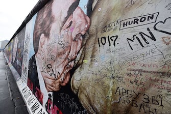 Graffiti cover the mural painting "My God, Help Me to Survive This Deadly Love" by Russian painter Dmitri Vrubel , depicting the kiss between then Soviet leader Leonid Brezhnev (L) and East German leader Erich Honecker at the East Side Gallery, a stretch of the Berlin wall, in Berlin on November 6, 2015. A quarter-century after the fall of the Berlin Wall, the city announced it would build a barrier to protect the longest surviving stretch from a sharp rise in vandalism.
AFP PHOTO / JOHN MACDOUGALL        (Photo credit should read JOHN MACDOUGALL/AFP via Getty Images)