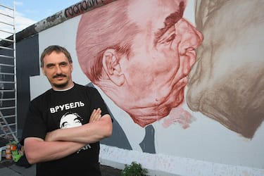 BERLIN - JUNE 22:  Russian artist Dmitry Vrubel poses in front of his work in progress showing former Soviet leader Leonid Brezhnev (L) kissing former communist East German leader Erich Honecker at a surviving portion of the Berlin Wall on June 22, 2009 in Berlin, Germany. The mural is on a portion of the Wall known as the East Side Gallery, and city authorities have invited artists to redo their works as part of a restoration effort. The Berlin Wall was built by the East German government and divided East and West Berlin from 1961 until 1989. Germany will mark 20 years since the fall of the Berlin Wall this year with an international commemoraiton in November.  (Photo by Sean Gallup/Getty Images)