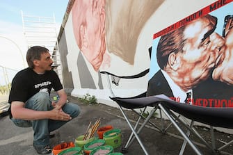 BERLIN - JUNE 22:  Russian artist Dmitry Vrubel preparees to continue painting his work in progress showing former Soviet leader Leonid Brezhnev (L) kissing former communist East German leader Erich Honecker at a surviving portion of the Berlin Wall on June 22, 2009 in Berlin, Germany. The mural is on a portion of the Wall known as the East Side Gallery, and city authorities have invited artists to redo their works as part of a restoration effort. The Berlin Wall was built by the East German government and divided East and West Berlin from 1961 until 1989. Germany will mark 20 years since the fall of the Berlin Wall this year with an international commemoraiton in November.  (Photo by Sean Gallup/Getty Images)