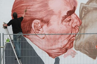 BERLIN - JUNE 22:  Russian artist Dmitry Vrubel repaints his historic mural showing former Soviet leader Leonid Brezhnev (L) kissing former communist East German leader Erich Honecker at a surviving portion of the Berlin Wall on June 22, 2009 in Berlin, Germany. The mural is on a portion of the Wall known as the East Side Gallery, and city authorities have invited artists to redo their works as part of a restoration effort. The Berlin Wall was built by the East German government and divided East and West Berlin from 1961 until 1989. Germany will mark 20 years since the fall of the Berlin Wall this year with an international commemoraiton in November.  (Photo by Sean Gallup/Getty Images)