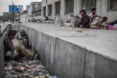 24 September 2021, Afghanistan, Kabul: An Afghan man sits in a littered ditch as others consume drugs on the side of a road in Kabul. Photo: Oliver Weiken/dpa (Photo by Oliver Weiken/picture alliance via Getty Images)