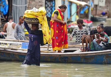 Flood-affected residents of a low lying area on the banks of the River Ganges move their belongings to drier ground at Daraganj area in Allahabad on August 19, 2022, after water levels rose following monsoon rains. (Photo by SANJAY KANOJIA / AFP) (Photo by SANJAY KANOJIA/AFP via Getty Images)