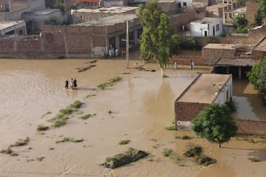 Residents wade through a flood hit area following heavy monsoon rains in Charsadda district of Khyber Pakhtunkhwa on August 29, 2022. - The death toll from monsoon flooding in Pakistan since June has reached 1,061, according to figures released on August 29, 2022, by the country's National Disaster Management Authority. (Photo by Abdul MAJEED / AFP) (Photo by ABDUL MAJEED/AFP via Getty Images)