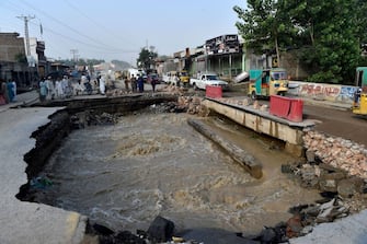 Residents gather beside a road damaged by flood waters following heavy monsoon rains in Charsadda district of Khyber Pakhtunkhwa on August 29, 2022. - The death toll from monsoon flooding in Pakistan since June has reached 1,061, according to figures released on August 29, 2022, by the country's National Disaster Management Authority.  (Photo by Abdul MAJEED / AFP) (Photo by ABDUL MAJEED / AFP via Getty Images)