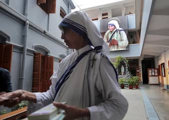 epa10160668 A nun distributes picture cards of Mother Teresa after a mass prayer at Mother House on Mother Teresa's 25th death anniversary in Kolkata, India 05 September 2022. Mother Teresa who died on 05 September 1997, at the age of 87, was popularly known as the 'Saint of the Gutter' for her extraordinary love and dedication to poor, homeless and diseased people.  She won the Nobel Peace Prize in 1979. Mother Teresa was canonized as a saint by Pope Francis in 2016. EPA / PIYAL ADHIKARY