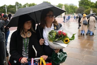 Well-wishers bring flowers as the rain falls outside Buckingham Palace, central London, on September 8, 2022. - Fears grew on September 8, 2022 for Queen Elizabeth II after Buckingham Palace said her doctors were "concerned" for her health and recommended that she remain under medical supervision. The 96-year-old head of state -- Britain's longest-serving monarch -- has been dogged by health problems since last October that have left her with difficulties walking and standing. (Photo by Daniel LEAL / AFP) (Photo by DANIEL LEAL/AFP via Getty Images)