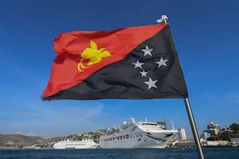 PORT MORESBY, PAPUA NEW GUINEA - NOVEMBER 13: The national flag of PNG flies in front of P & O's Pacific Explorer (foreground) and Pacific Jewel berthed on November 13, 2018 in Port Moresby, Papua New Guinea.  Highlighting Carnival Australia's long-standing committment to the Pacific and PNG, three of the company's ships are supporting PNG's successful hosting of APEC 2018 in the national capital with two of the ships already in port to be joined by Princess Cruises' Sea Princess on Wednesday.  It is seen as a natural extension of the company's local cruise activity making 250 port calls from 2016-2018 bringing 400,000 visitors to PNG.  (Photo by James D. Morgan / Getty Images for Carnival Australia)
