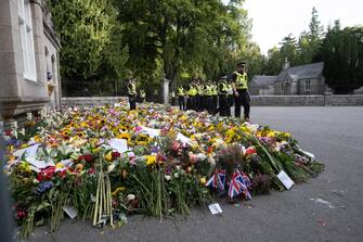 epa10177289 Police stand next to flowers left in tribute to Britain's late Queen Elizabeth II outside Balmoral Castle, Scotland, Britain, 11 September 2022. Britain's Queen Elizabeth II died at her Scottish estate on 08 September. The late queen will lie in state for 24 hours at St Giles' Cathedral in Edinburgh.  EPA/PAUL REID
