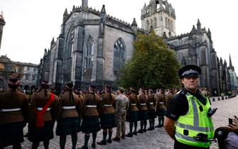 A Police officer stands guard as members of the Royal Regiment of Scotland rehearse on the eve of the Royal Mile outside of St Giles' Cathedral in Edinburgh on September 10, 2022, two days after Queen Elizabeth II died at the age of 96. - King Charles III pledged to follow his mother's example of "lifelong service" in his inaugural address to Britain and the Commonwealth on Friday, after ascending to the throne following the death of Queen Elizabeth II on September 8. (Photo by Odd ANDERSEN / AFP) (Photo by ODD ANDERSEN/AFP via Getty Images)