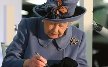 Britain's Queen Elizabeth II signs the visitor's book during her visit to the Siemens Gamesa Renewable Energy wind turbine blade factory in Kingston upon Hull, in northern England on November 16, 2017. (Photo by Lindsey Parnaby / POOL / AFP) (Photo by LINDSEY PARNABY/POOL/AFP via Getty Images)