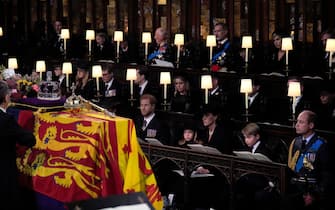 (front row, left to right) The Duke of Sussex, Princess Charlotte, the Princess of Wales, Prince George, and the Prince of Wales, watch as the Imperial State Crown and the Sovereign's orb and sceptre are removed from the coffin of Queen Elizabeth II, draped in the Royal Standard, during the Committal Service at St George's Chapel in Windsor Castle, Berkshire. Picture date: Monday September 19, 2022.
