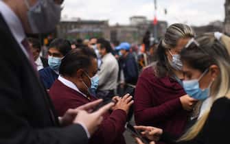 People use their phones as they remain in the street after an earthquake in Mexico City on September 19, 2022. - A 6.8-magnitude earthquake struck western Mexico on Monday, shaking buildings in Mexico City on the anniversary of two major tremors in 1985 and 2017, seismologists said. (Photo by Pedro PARDO / AFP) (Photo by PEDRO PARDO/AFP via Getty Images)