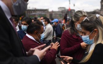 People use their phones as they remain in the street after an earthquake in Mexico City on September 19, 2022. - A 6.8-magnitude earthquake struck western Mexico on Monday, shaking buildings in Mexico City on the anniversary of two major tremors in 1985 and 2017, seismologists said. (Photo by Pedro PARDO / AFP) (Photo by PEDRO PARDO/AFP via Getty Images)