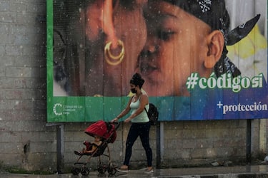 A woman and her baby walk past a banner in favor of the new Family Code referendum under the rain in Havana, on September 23, 2022. - Cubans will vote on Sunday in a referendum on whether to allow same-sex marriage and surrogate pregnancies, which experts say could turn into an opportunity to voice opposition against the government. (Photo by YAMIL LAGE / AFP) (Photo by YAMIL LAGE/AFP via Getty Images)
