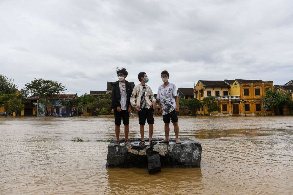 TOPSHOT - Boys stand on a rock on a flooded street after Typhoon Noru made landfall in Hoi An, Vietnam's Quang Nam Province on September 28, 2022. (Photo by Nhac NGUYEN / AFP) (Photo by NHAC NGUYEN/AFP via Getty Images)