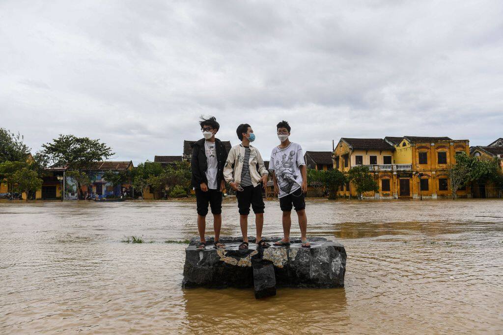 1243564345 TOPSHOT - Boys stand on a rock on a flooded street after Typhoon Noru made landfall in Hoi An, Vietnam's Quang Nam Province on September 28, 2022. (Photo by Nhac NGUYEN / AFP) (Photo by NHAC NGUYEN/AFP via Getty Images)
