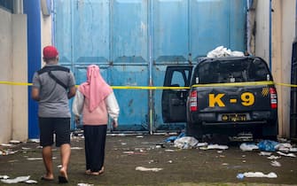 epa10218847 People look at a damaged police truck outside Kanjuruhan stadium in Malang, East Java, Indonesia, 02 October 2022. At least 127 people including police officers were killed mostly in stampedes after a clash between fans of two Indonesian soccer teams, according to the police.  EPA/SANDI SADEWA